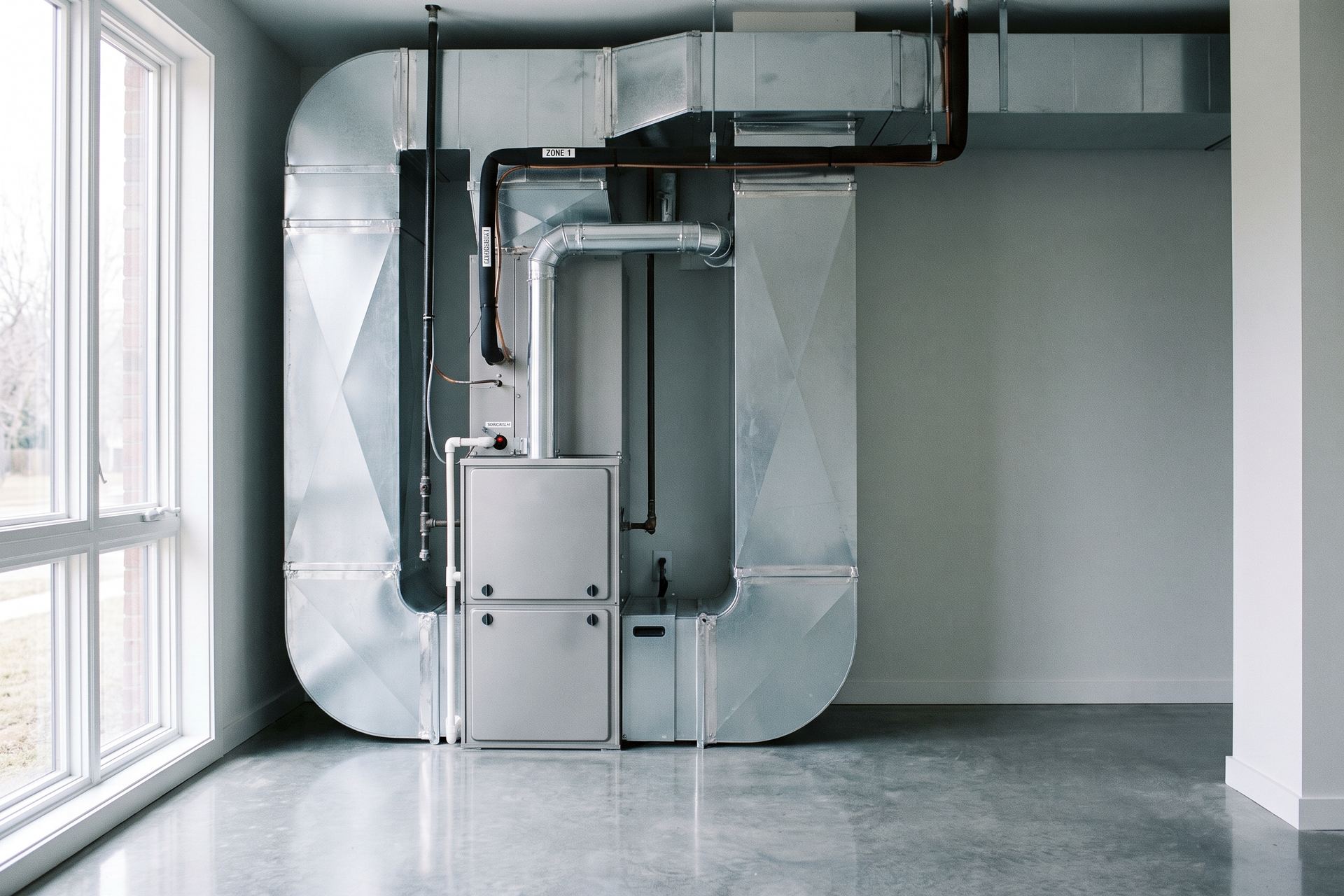 A newly installed high-efficiency furnace and sheet-metal ductwork in a clean utility room.